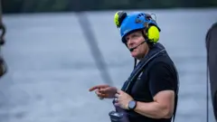 David Lochridge com equipamentos de proteção. Atrás, está o mar.