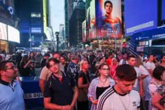 New York, des gens prennent des photos du coucher de soleil sur la 42e rue à Times Square pour admirer ce que l'on appelle le « Manhattanhenge », lorsque le soleil s'aligne parfaitement entre les bâtiments du réseau routier de la ville de New York.