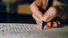 Mão escreve com caneta em um caderno pautado