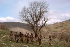 Um grupo de combatentes femininas desce a colina após um exercício militar.