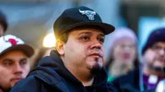 黒字に灰色のシカゴ・ブルズのロゴがついたキャップをかぶり、黒いパーカーを着たアブレゴ＝ガルシア氏が目元に涙を浮かべ、支持者に囲まれている