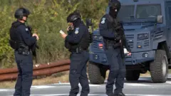 Tri muškarca u policijskoj uniformi pored službenog automobila, jedan od njih pregleda dokumenta