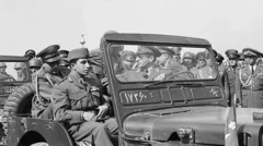 شاه ایران پشت فرمان یک جیپ نظامی در کنار ملک فیصل دوم، آخرین پادشاه عراق، در جریان بازدید از یک مانور نظامی در ایران 