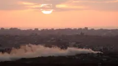 Fumaça se ergue da Faixa de Gaza com o pôr do sol, visto do lado israelense da fronteira em 30 de julho de 2025