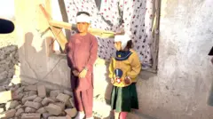 کودکانی که در حملات هوایی پاکستان در پل‌چرخی زخمی شده‌اند سرشان با بانداژ پیچانده شده و در مقابل کلکین یک خانه ویران در مقابل کمره ایستاده‌اند. ۱۳ مارچ ۲۰۲۶ کابل، پل‌چرخی