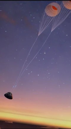 අහසේ කෝප්පයක් හති වස්තුවක් පැරෂුට් දෙකකින් එල්ලී තිබෙන ආකාරය පෙනේ.