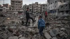 Palestinian boys are seen in the rubble of a building destroyed by an Israeli attack in Rafah, Gaza on 3 January 2024