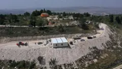Vista aérea mostrando pessoas ao redor de um prédio modular em construção no posto avançado de colonos em Homesh, perto do vilarejo palestino de Burqa, na Cisjordânia ocupada (29 de maio de 2023)