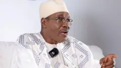 Cameroon presidential candidate Issa Tchiroma Bakary in a white gown, wearing glasses
