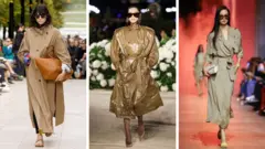 Três modelos vestem um trench coat amplo em marrom-claro suave (à esquerda), um trench coat brilhante em tom claro de marrom (centro) e um casaco de aspecto mais próximo ao de um vestido, sem botões, também em marrom claro (à direita)