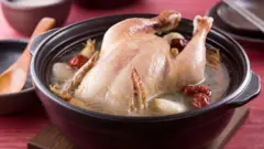 Frango inteiro cozido em panela de barro com caldo, tâmaras vermelhas e alho.