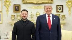 Усміхнені Зеленський і Трамп позують для спільного фото в розкішно оздобленому кабінеті. На задньому плані видно камін, декоративні золотисті елементи інтер’єру, портрети в рамках і моделі літаків.