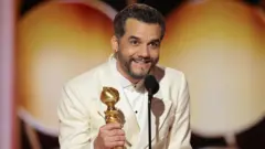 Wagner Moura com uma estatueta na mão e falando ao microfone após ser premiado, na cerimônia do Globo de Ouro, rem 11 de janeiro de 2026.