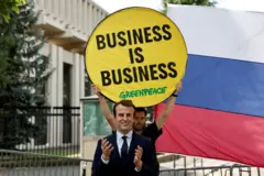 voštana figura Emanuela Makrona iza koje aktivista drži transparent „Posao je posao"