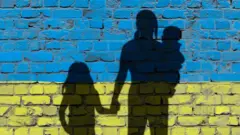 Силуети жінки з дітьми на фоні українського прапора
