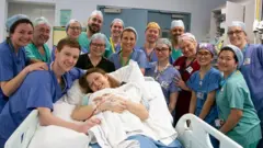 Bebê nos braços da mãe cercada pela equipe médica