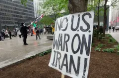 Плакат с надписью «нет войне США с Ираном», на заднем плане человек с флагом США, дальше человек с флагом Мексики и Палестины