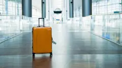 黄色いプラスチック製のスーツケースが、駅の通路と思われる場所に置いてある資料写真