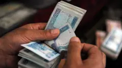 دوه لاسونه ښکاري چې د افغانیو پنځه‌سوییز بنډل شماري.