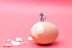 Boneco em miniatura quebrando a casca de um ovo cozido