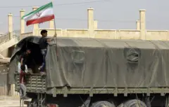 یک نوجوان سوری با پرچم ایران در دیرالزور؛ ایران در این منطقه نفوذ بالایی دارد