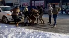 雪の積もる路上に倒された男性を連邦職員が取り囲んでいる