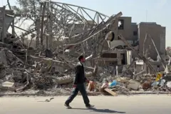 Un hombre camina por los escombros de unos edificios destruidos