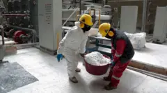 Trabalhadores carregam um balde de carbonato de lítio no salar de Uyuni