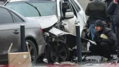 Una persona observa cerca del carro blanco que sufrió daños por la explosión.