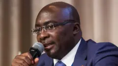 Mahamudu Bawumia, vêtu d'un costume bleu et d'une cravate, tenant un microphone