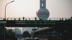 Uma tela em uma ponte de pedestres mostra dados financeiros em Xangai, China