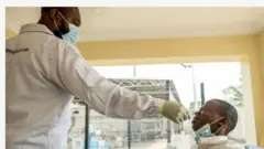 Aworan oisṣẹ eleto ilera to n ṣayẹwo arun Covid 19 fun ẹnikan to jokoo