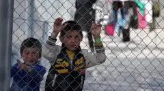 Два мальчика за сетчатым забором центра сбора беженцев