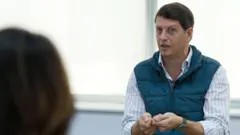 Foto de Ricardo Salles, vestindo uma camisa azul listrada e um colete azul por cima.