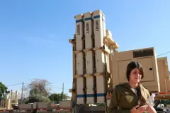 Uma reservista israelense ao lado de uma bateria do sistema de defesa aérea Estilingue de David