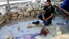 فلسطيني ينظر إلى دماء على الأرض في أعقاب اشتباك مع مستوطن إسرائيلي، في قرية أم الخير، بالقرب من مدينة الخليل في الضفة الغربية المحتلة بتاريخ 29 يوليو/تموز 2025