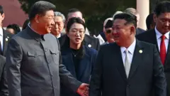 2025年9月3日，在北京天安門廣場舉行的紀念抗戰勝利80周年閱兵前，中國國家主席習近平（左）觸碰朝鮮領導人金正恩的手肘。