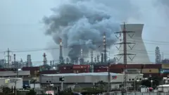 ईरान के साथ अमेरिका-इसराइल संघर्ष के बीच, 19 मार्च, 2026 को इसराइल के हाइफा में एक तेल रिफाइनरी से धुआं उठ रहा है, जो ईरानी हमले में क्षतिग्रस्त हो गई थी.