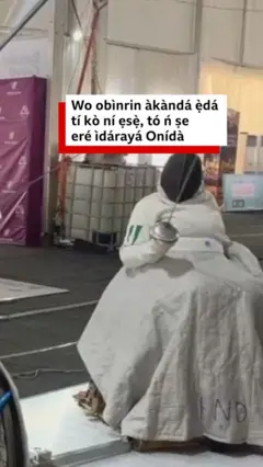 Aanu Kumuyi wọ asọ funfun, joko lori aga onirin, mu ida lọwọ