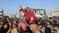 Manifestantes em Gaza entre escombros e prédios destruídos