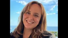 Ayşe Barım sadece yüzünün göründüğü resimde ekrana bakarak gülümsüyor. Arka planda deniz manzarası var.