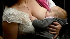 Женщина кормит грудью младенца