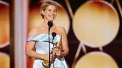 Jessie Buckley recebendo o Globo de Ouro de melhor atriz de filme dramático