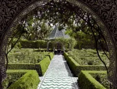 Fotografía exterior que muestra bordes de setos ordenados y un camino de baldosas verdes en zigzag.