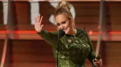 Adele acena com a estatueta do Grammyprograma de rádio zebetuma das mãos