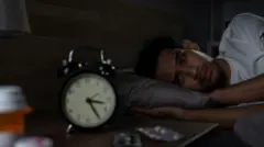 Homem deitado na cama à noite, acordado, olhando para o despertador que marca 3h25.