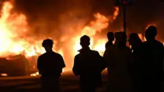  ألسنة اللهب تتصاعد إثر إشعال النار في عدد كبير من السيارات في منطقة راملز في روزنجارد، مالمو