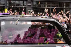 El carro fúnebre en el que transportaban el ataúd de Ozzy, mientras fanáticos les toman fotos.