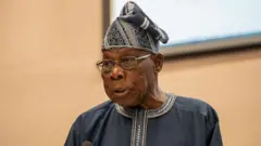 Olusegun Obasanjo wọ ẹwu pẹlu fila ati igo loju rẹ