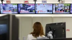 Telas de televisão mostram danos após um terremoto de magnitude preliminar de 7,1 atingir a província de Kumamoto, no sul do Japão; imagem registrada em Tóquio, no Japão, em 28 de julho de 2026.